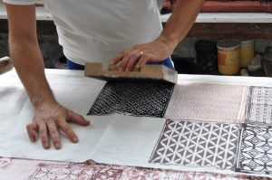 Artisan decorating a linen table runner through wood-block print technique