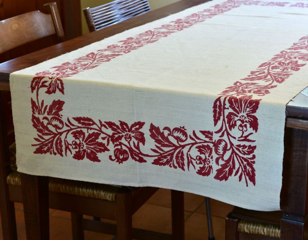 Farmhouse table runner with hand-printed pomegranate design laid on a wooden kitchen table