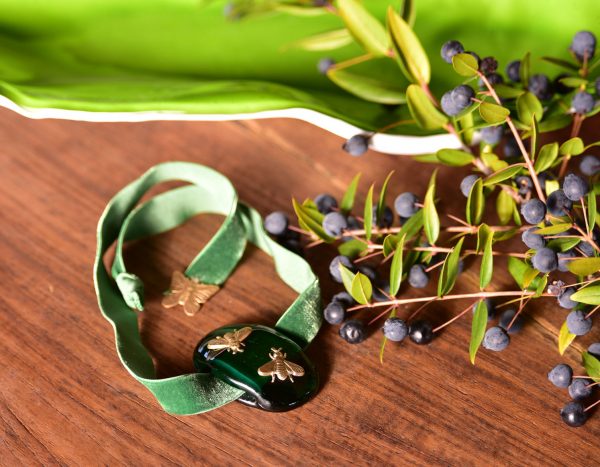 Handmade Murano Glass Bracelet Hope Green - Bracelet is laying on wooden table with leaves to the side