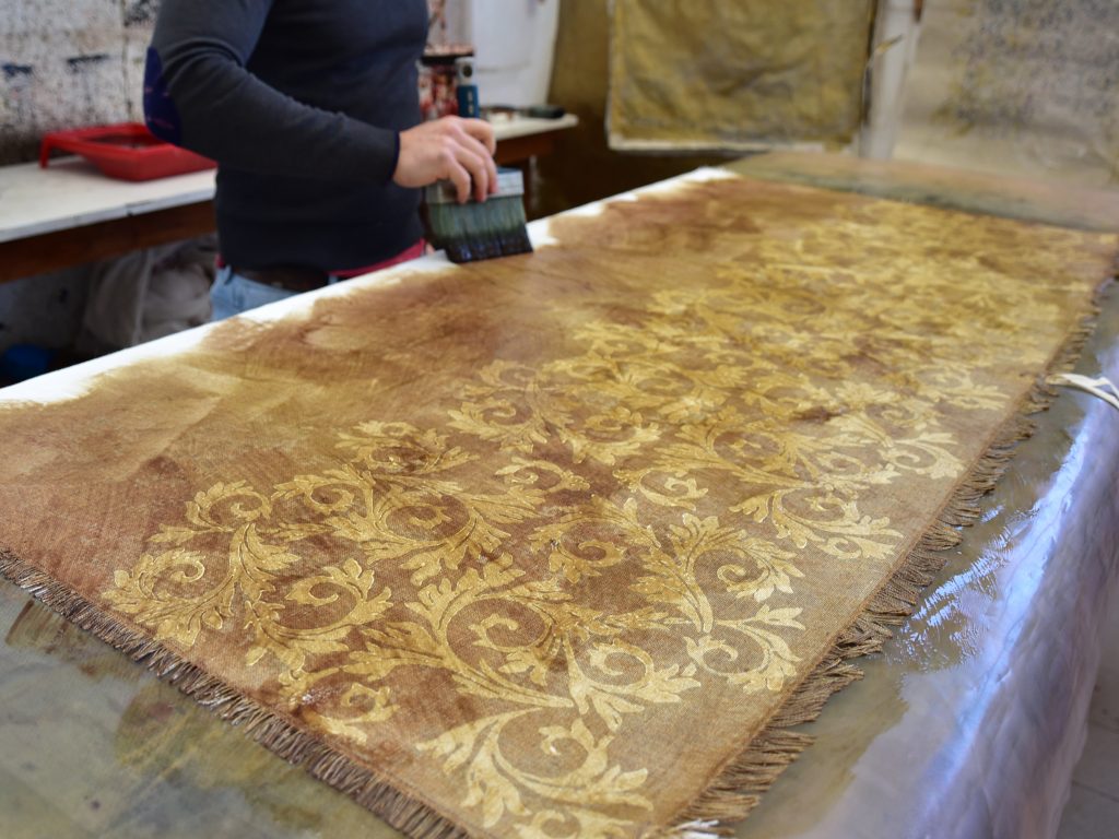 Linen Throw - Hand-painted and Hand-printed - Acanthus Leaves/Lime Green - Photo shows the process of creation, the craftsmen are using a method known as 'negative printing', ‘negative printing’, during which designs are painted onto the organic linen using wax