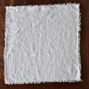 hemp napkin (light cream) - hemp linen napkin with fringes - image displays napkin laid out on wooden floor