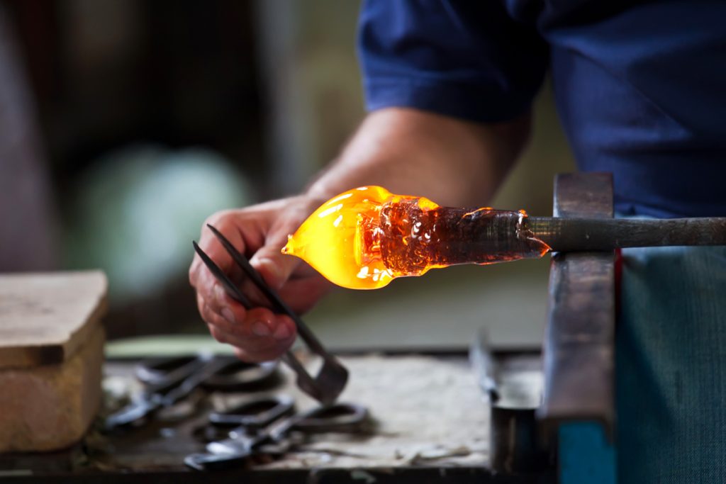 Murano glass in a molten state, being manipulated by an artisan by hand