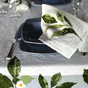 Camellia organic linen napkin placed atop a bowl at a table setting. The bowl and cutlery sit atop the organic linen tablecloth from the Camellia collection