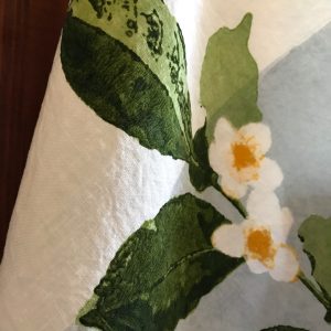 Close-up detailing of the motifs of the Camellia organic linen tea towel with band.