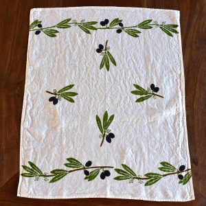 Linen Tea Towel, Block-Printed - Olives. Image displays tea towel laid out across wooden surface.