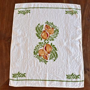 Organic Linen Tea Towel - Pomegranate. Image displays tea towel laid out across wooden table