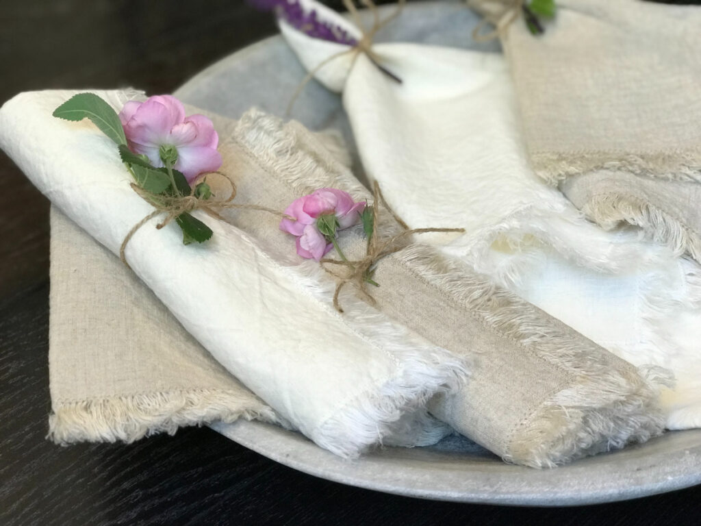 Hemp Linen Napkins with Fringes - the napkins are rolled up inside a napkin ring, with a flower protruding