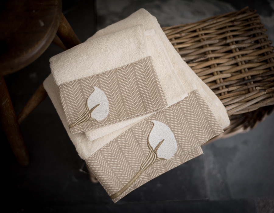 Cream coloured cotton towels folded on top of a wicker basket
