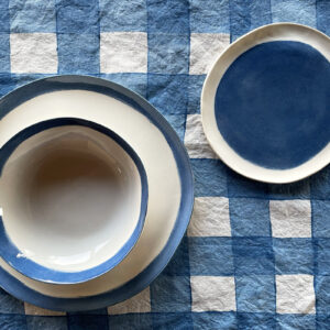 Hand painted porcelain set on a blu checked linen placemat
