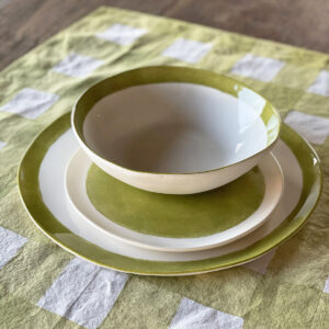 hand painted green porcelain dinner set displayed on a linen checked placemat