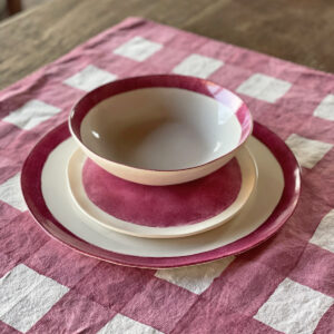 hand painted porcelain dinner set pink laid on a checked placemat