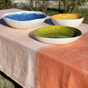 hand-painted orange linen tablecloth with serving porcelain bowls displayed on top