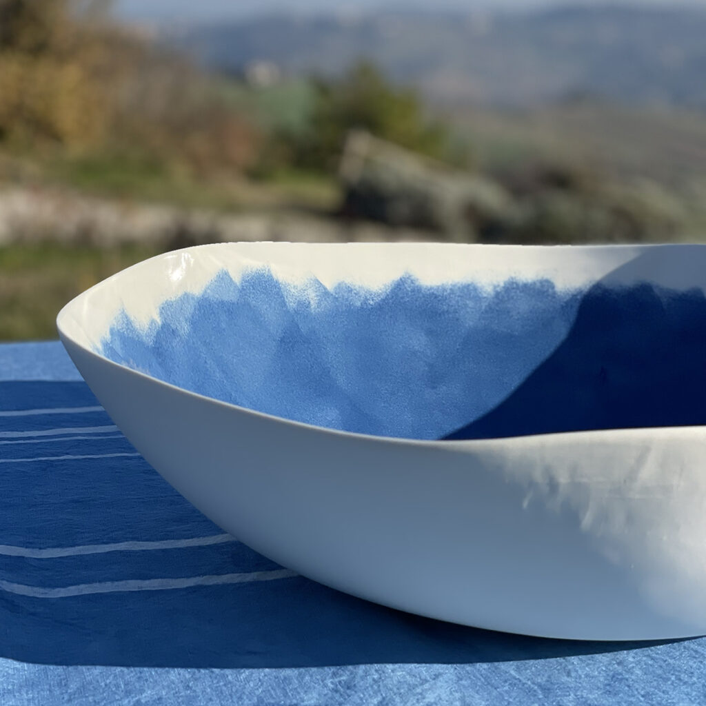 Blue painted porcelain serving bowl on a blue linen tablecloth