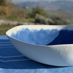 Blue painted porcelain serving bowl on a blue linen tablecloth