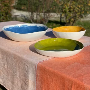 Blue, yellow and green serving bowls on an orange tablecloth