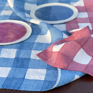 Checked linen tea towels laid on table with and porcelain dinnerware on top