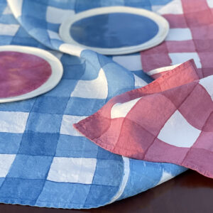 Checked linen tea towels laid on table with and porcelain dinnerware on top