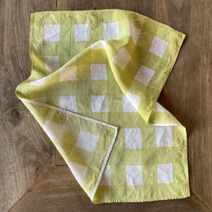 Green checked linen tea towel laid on a wooden table
