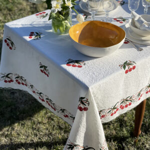 linen tablecloth with cherry design dressed with porcelain crockery and a vase of flower