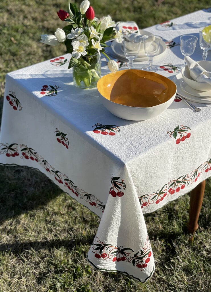 linen tablecloth with cherry design dressed with porcelain crockery and a vase of flower