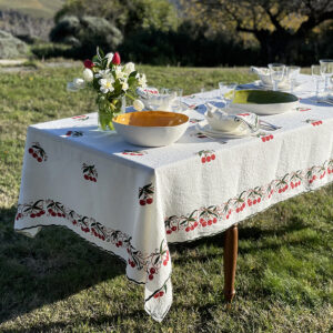 Cherry linen tablecloth dressed with a vase of flowers and handmade porcelain