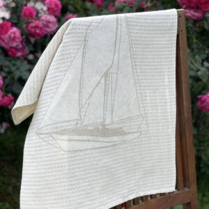 Nautical blue italian jacquard kitchen towel laid on a chair with roses in the background