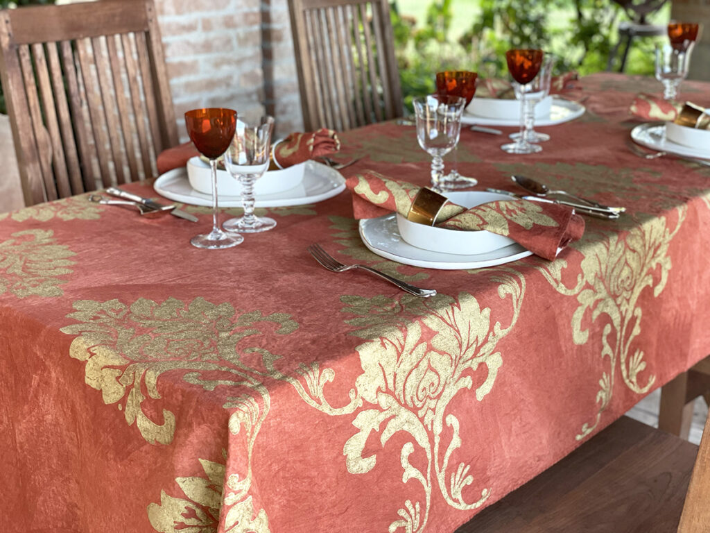 Hand-painted gold linen tablecloth with Limoges porcelain plates and red vintage glass wine on top