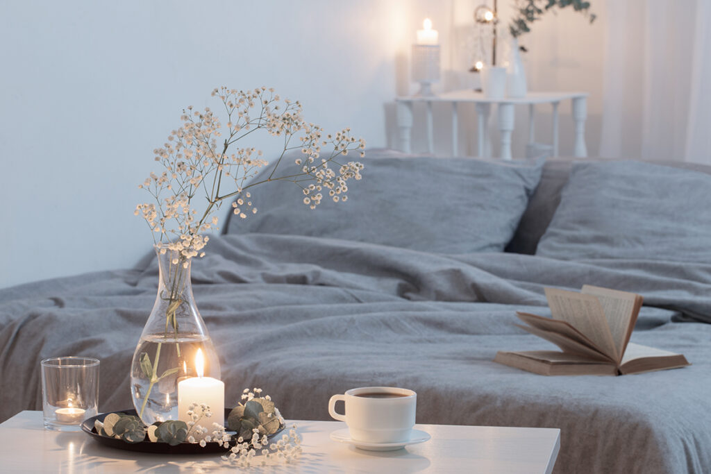 night interior of a small and cosy bedroom with flowers and burning candles