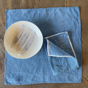 Hand-painted blue linen napkin with a porcelain bowl on top
