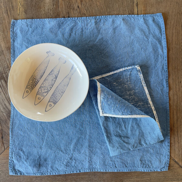 Hand-painted blue linen napkin with a porcelain bowl on top