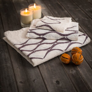 Linen bath towels laid on wood with lit candles and props on the side