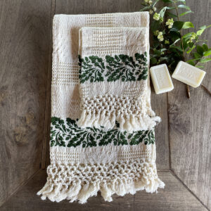 Cotton Jacquard towel laid on a wooden table with soap bars and flowers on the side