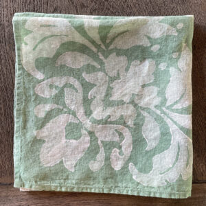 folded linen napkins in teal colour with white motif