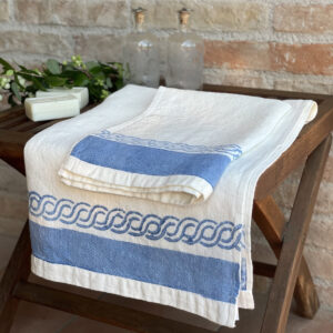 linen bath towels laid on a wooden bench with soap bars and flowers on the side