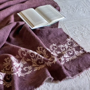 plum linen throw laid on a bed with an open book on the side