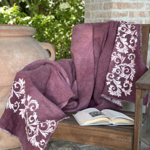 plum linen throw laid on a wooden chair with a book open onto the seat