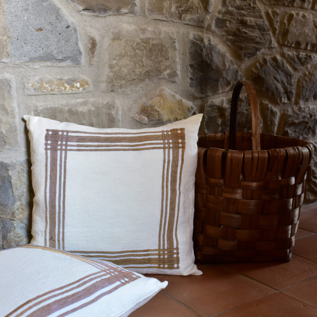 Cosy linen cushions in brown stripes design laid by a stone wall