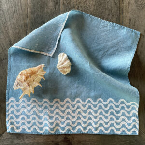 coastal blue linen napkin with waves motif and sheets laid onto it