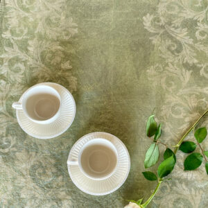 green linen napkin with two porcelain cups and a roses on top