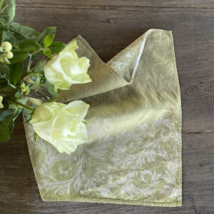 Green napkin laid on a wooden table with yellow roses on the side