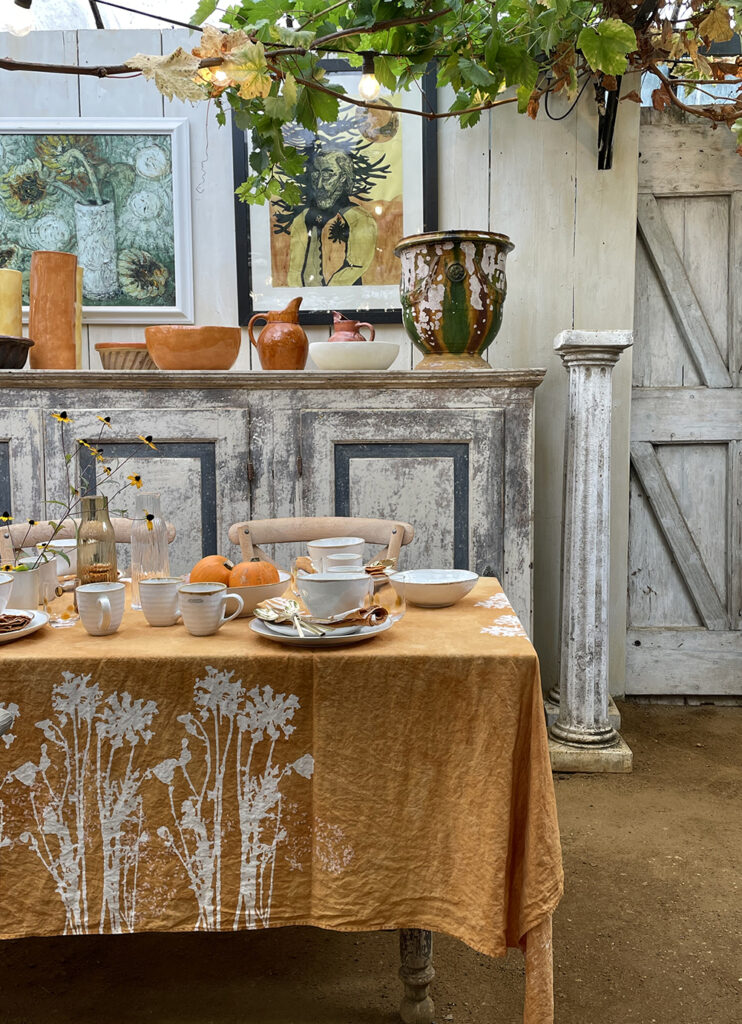 artisan made linen tablecloth with unique crockeries laid on vintage cabinet
