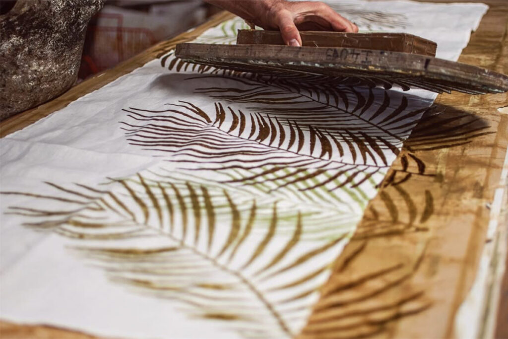 artisan block-printing a linen table runner in palm design