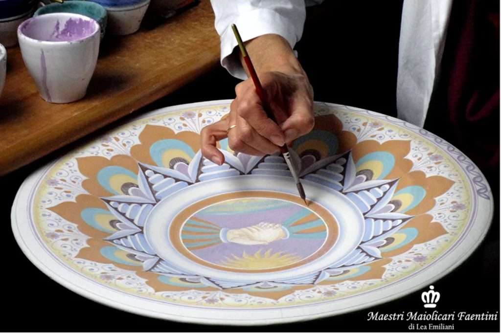 Italian artisan from Faenza painting by hand a ceramic platter