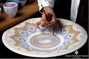 Italian artisan from Faenza painting by hand a ceramic platter