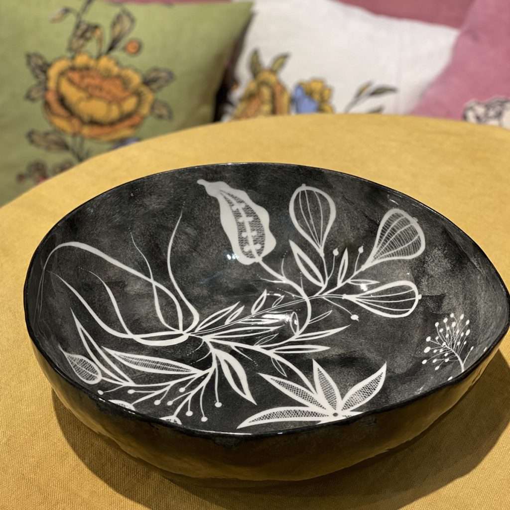 Italian handmade black ceramic bowl laid on a table with a yellow tablecloth