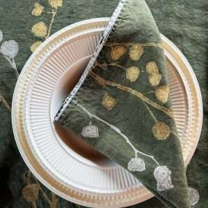 Hand-painted linen napkin in dark olive-green with a block printed floral motif in gold and silver