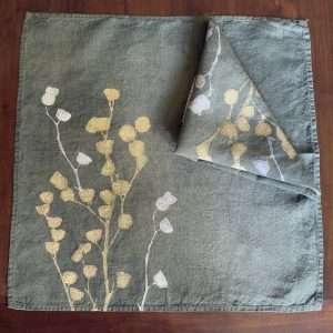 Luxury linen napkin in dark green with botanical motif printed onto it