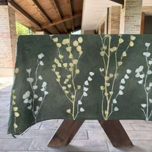 Green linen tablecloth laid on a wooden table under an italian portico