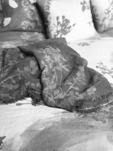 linen throws and linen cushion in botanical design laid on a bed