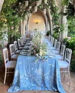 Long linen tablecloth for a wedding laid on a table alfresco with bouquet of flowers on top